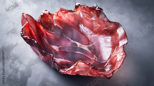 Obraz na płótnie A rose quartz slice with natural swirl patterns, photographed on a dark surface against a light background. w salonie