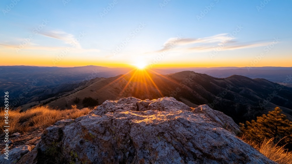 Obraz premium Mountain peak vista with sunburst at dawn, golden light, rocky foreground
