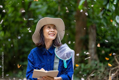 Asian biologist is collecting data in forest field study of mud puddling phenomenon butterfly sapping on salt and mineral during summer during mating season in tropical rainforest wild entomology photo