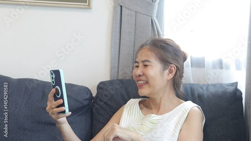 woman smiling while video chatting, holding phone