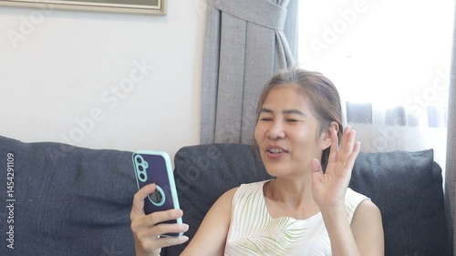 woman smiling while video chatting, holding phone