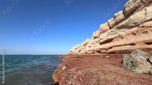 Wallpaper Mural Turquoise waters washing crimson rocky shores of Hormuz Island, exposing unique geological formations beneath clear azure skies in Persian Gulf landscape Torontodigital.ca
