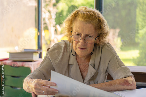 Senior woman reading documents at home office