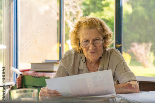 Senior woman reading documents at home office desk