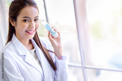 Attractive young Asian scientist woman lab technician assistant analyzing sample in test tube at laboratory. Medical, pharmaceutical and scientific research and development concept