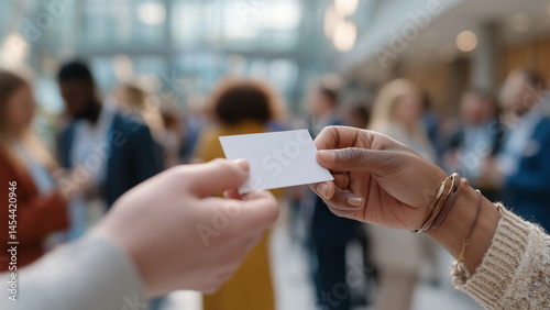 Close-up of hands exchanging white empty business cards at a networking event, blurred crowd in the background, natural lighting.