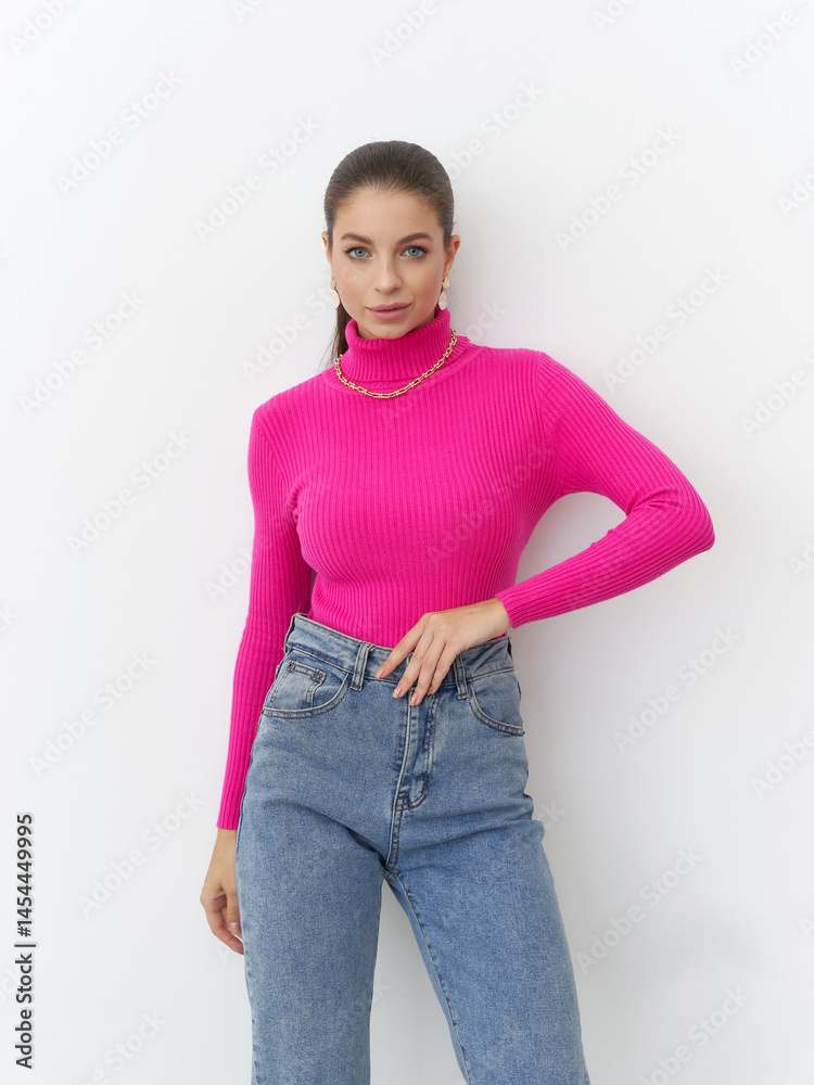 Fototapeta premium Striking pose of a confident woman in vibrant pink sweater at a modern studio setting