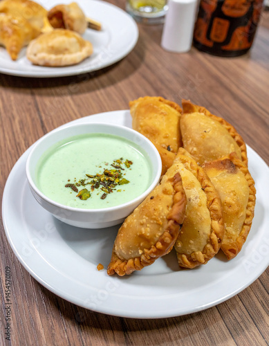 A Saudi plate of freshly made sambusak pastries alongside a dipping mint yogurt sauce. photo
