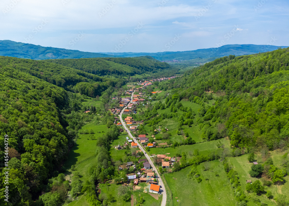 Aerial view of a village between hills with forests in Transylvania - Romania