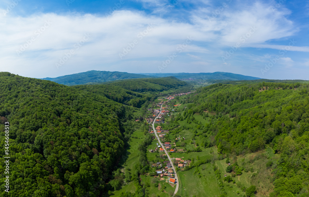 Aerial view of a village between hills and green forests