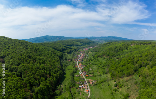 Obraz na płótnie Aerial view of a village between hills and green forests w salonie