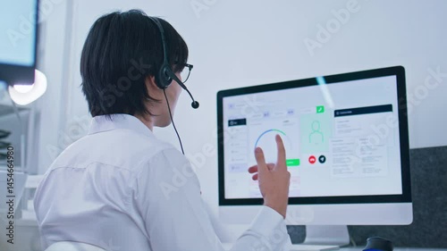 Caucasian male Professional call center agent with headset work in office, looking at computer display monitoring client detail, consulting service, talking online support in customer support office.