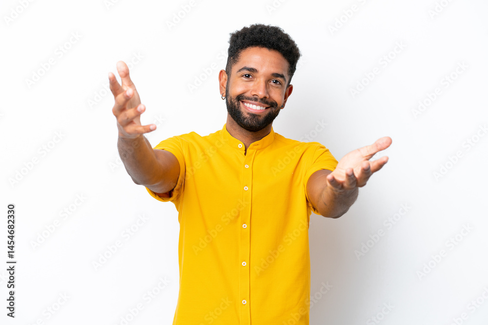 Young Brazilian man isolated on white background presenting and inviting to come with hand
