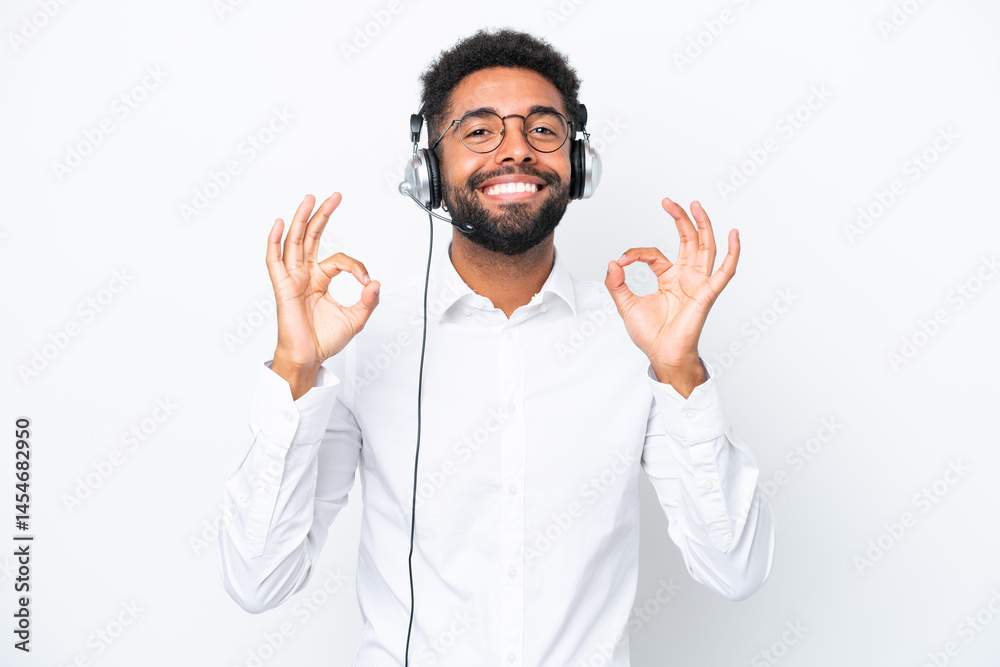 Telemarketer Brazilian man working with a headset isolated on white background showing an ok sign with fingers