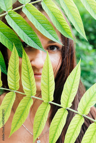 Portrait of a brown-eyed woman in the green foliage of a tree