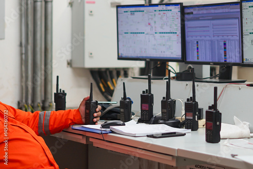 Slika na platnu Operator actively monitoring systems and communicating via walkie talkie in indu