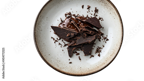 Dark chocolate chunks and shavings on a speckled plate against a white background seen from above