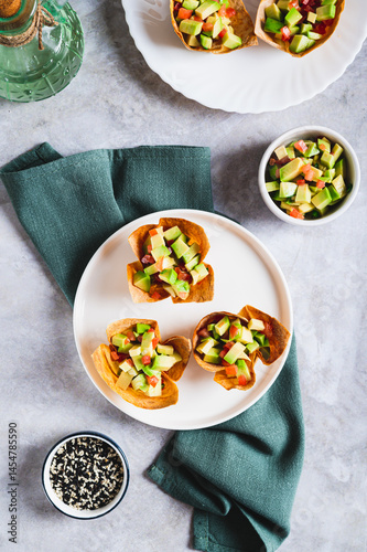 Mini baked pita cups with guacamole on a plate on a table top and vertical view