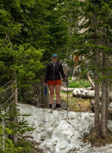 Woman Pauses on Snow Bank in Forest in Rocky Mountain Wilderness