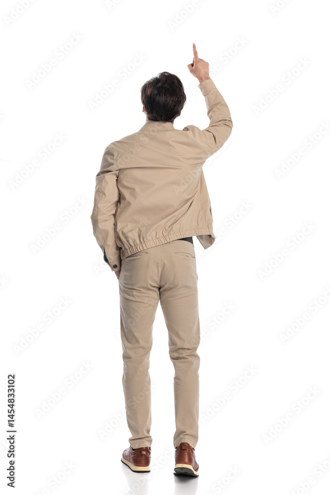 Naklejka premium behind view of casual guy pointing finger to the sky while stepping