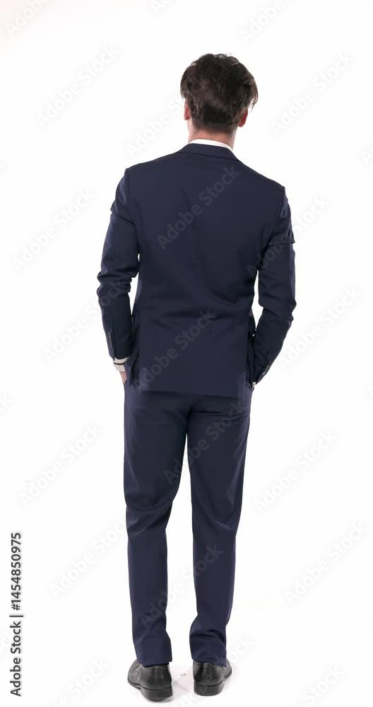 back view of elegant businessman in navy blue suit holding hands in pockets and moving in front of white background back view of elegant businessman in navy blue suit holding hands in pockets and moving in front of white background