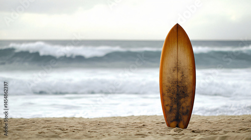 A surfboard standing upright in the sand with gentle waves in the background.
