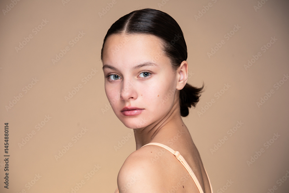Beauty portrait of teen girl against beige background.