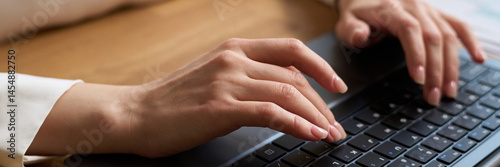 Obraz na płótnie High angle closeup of hands of unrecognizable young woman typing on laptop while sitting at desk in office, header w salonie