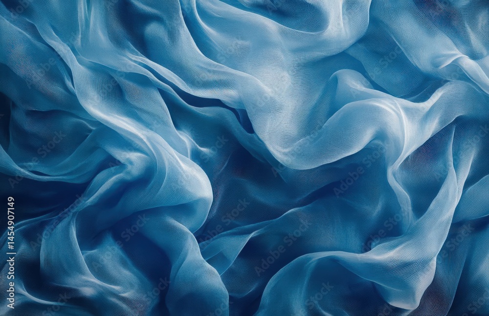 Obraz premium Top view of flowing blue silk fabric with wavy texture, creating an abstract background ideal for fashion design and product decoration.