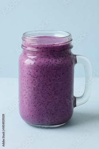 Delicious Purple Smoothie in a Glass Jar With a Handle on a Plain Background