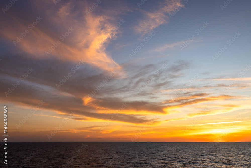 A dramatic set of clouds, at sunset, drifting over the tropical waters of the Caribbean Sea are lit by the last moments of daylight A dramatic set of clouds, at sunset, drifting over the tropical waters of the Caribbean Sea are lit by the last moments of daylight