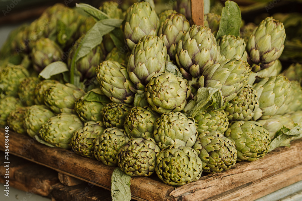Fototapeta premium A rustic display of fresh green artichokes stacked in a wooden crate at a market