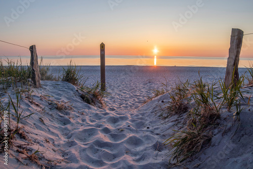 Fototapeta Naklejka Na Ścianę i Meble -  Sunset over the Baltic Sea at Darß Peninsula showcasing tranquil shoreline and sandy pathway