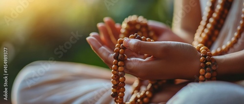 Yoga practitioner sits meditatively while holding chanting mala prayer beads, displaying serene concentration.