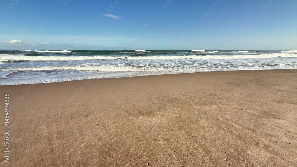 Fototapeta premium A Serene Beach Landscape Featuring Gentle Waves Lapping Against the Shore and a Clear Blue Sky