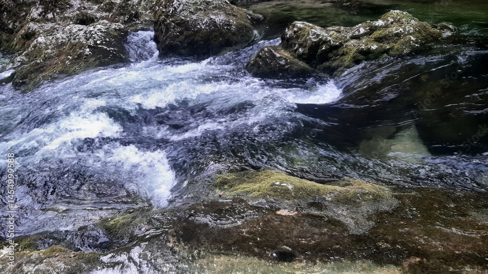 Flowing river water over rocks in a serene natural setting Flowing river water over rocks in a serene natural setting