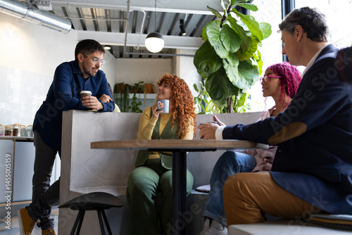 Coworkers chatting and drinking coffee during break in modern office