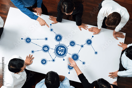 Tableau sur toile A diverse business team convenes around a table, actively collaborating on strategic management concepts illustrated with technology icons in a modern workspace