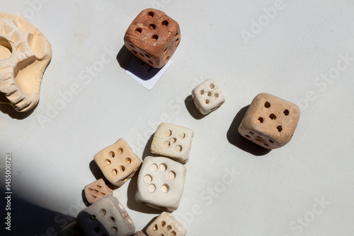 Handcrafted clay Roman dice are displayed for sale alongside a clay skull at  a table