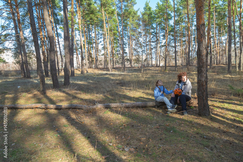 Wallpaper Mural Grandmother and granddaughter talking while sitting on log in forest holding sports ball on sunny day Torontodigital.ca