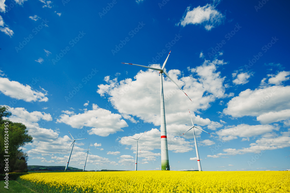 Wind energy generation using windmills. Electricity is produced by a wind turbine against a blue sky background. Energy production in a windy green area. Ecological energy production