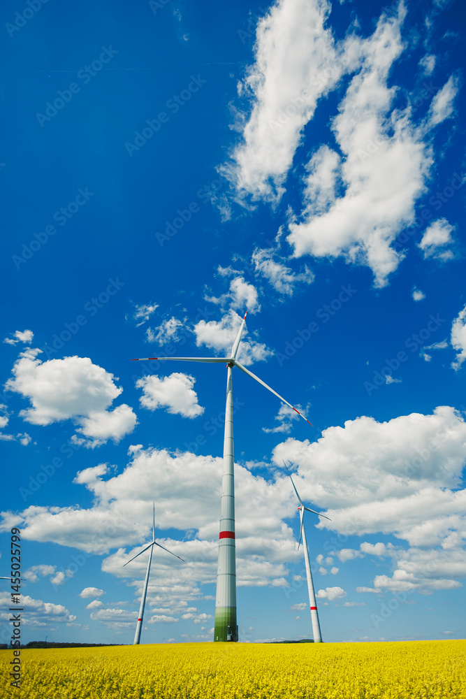 Wind energy generation using windmills. Electricity is produced by a wind turbine against a blue sky background. Energy production in a windy green area. Ecological energy production