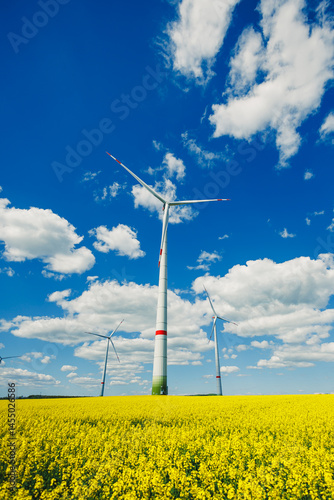 Obraz na płótnie Wind energy generation using windmills. Electricity is produced by a wind turbine against a blue sky background. Energy production in a windy green area. Ecological energy production w salonie