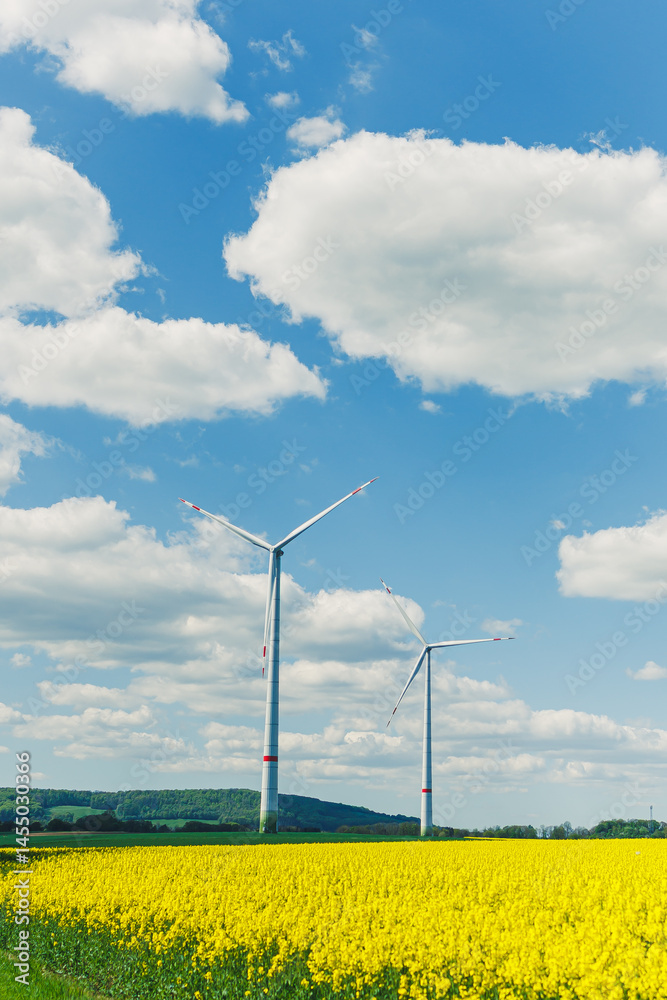 Ecological energy generation by windmills from the wind. Windmill field. Wind turbines generating energy against a clear blue sky. Wind turbines generating clean renewable energy in a rural field.
