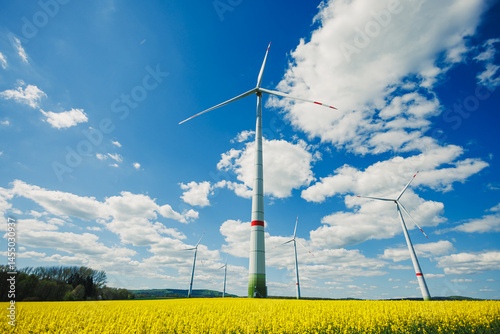 Obraz na płótnie Wind turbines in a yellow field against a blue sky. Ecological energy production by windmills in rural areas in Europe. w salonie