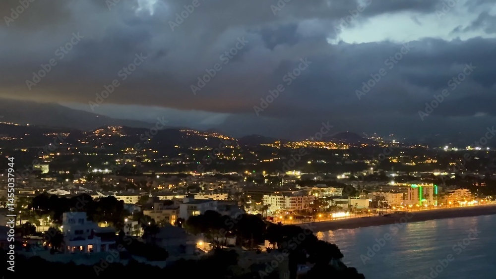 Enjoy a scenic night view of a coastal city with brightly illuminated buildings Enjoy a scenic night view of a coastal city with brightly illuminated buildings