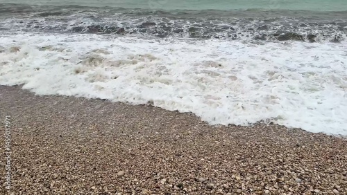 Experience serene beach waves lapping against a pebbly shoreline, perfect for relaxation