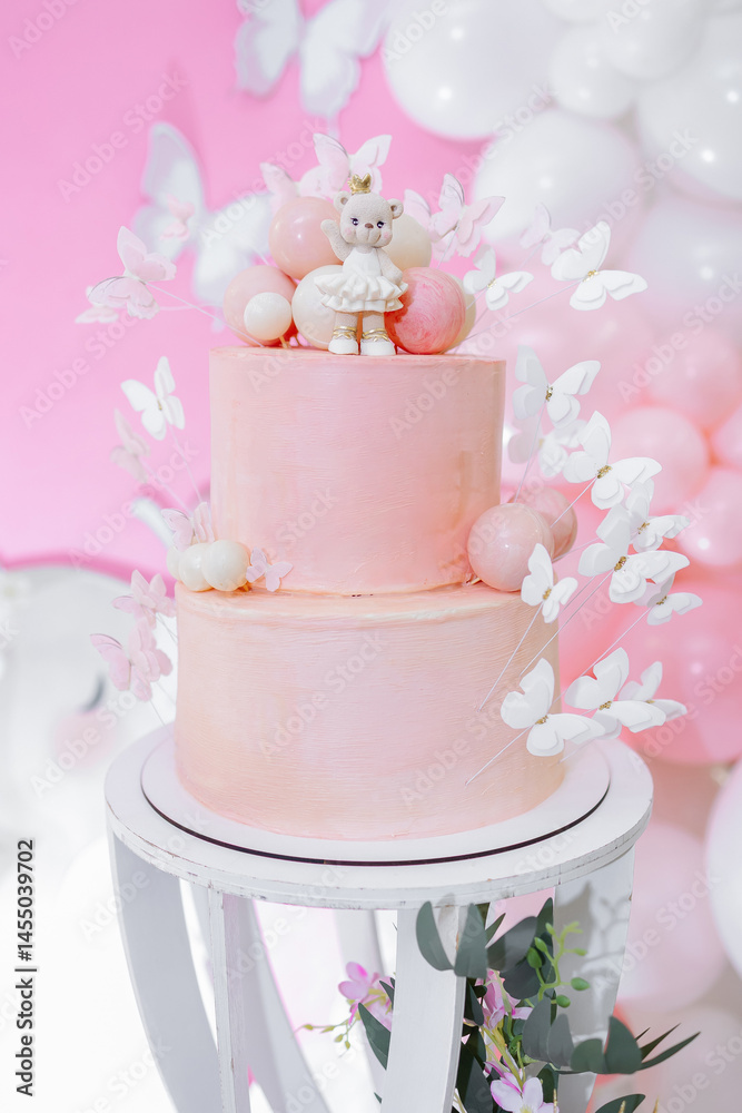 Pink first birthday cake with teddy bear figurine. Soft pastel colors and festive decoration create a warm, festive atmosphere. Sweet cake for a one-year-old birthday girl