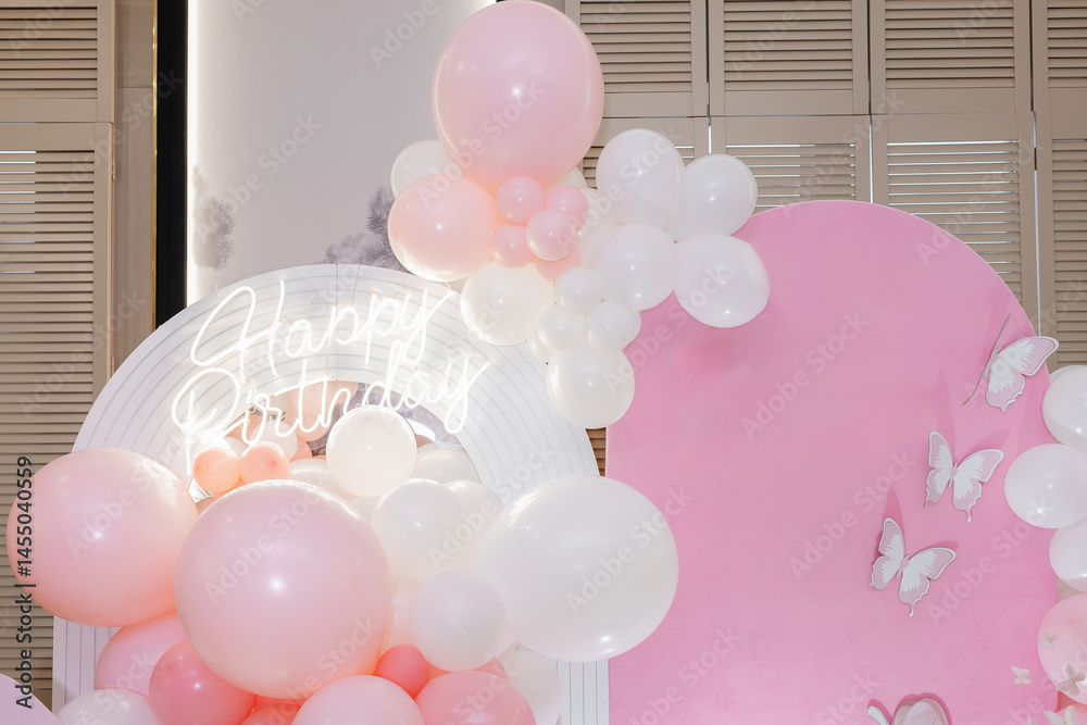 Pink photo zone for children's birthday with helium white balloons. Bright celebration of children's birthday with blue balloons.