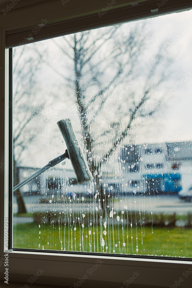 Professional cleaning worker washes windows with special equipment. Woman washes windows with mop and glass cleaner. House cleaning.